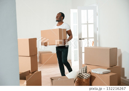 Happy black man is moving in his new home, holding box 132216267