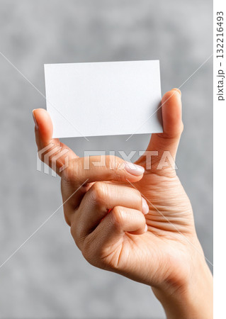 Hand holding blank business card against soft gray background, showcasing potential for branding and personal identity design concepts Hand holding blank business card against soft gray background, showcasing potential for branding and personal identity design concepts 132216493