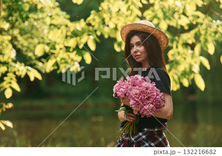 Beautiful young woman is with pink flowers in the park 132216682
