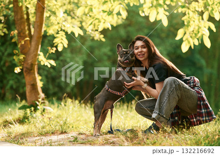 Sitting on the grass, embracing an animal. Young pretty woman is with her dog in the park Sitting on the grass, embracing an animal. Young pretty woman is with her dog in the park 132216692
