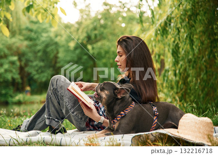 Story reading, red book. Young pretty woman is with her dog in the park Story reading, red book. Young pretty woman is with her dog in the park 132216718