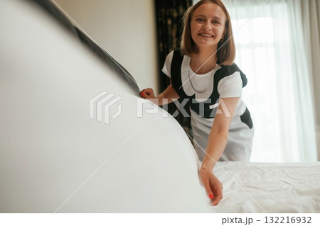 New cloth for bed. Young chambermaid is in hotel room New cloth for bed. Young chambermaid is in hotel room 132216932