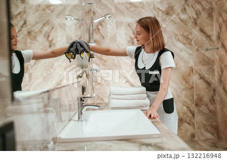 In the bathroom. Young chambermaid is in hotel room 132216948