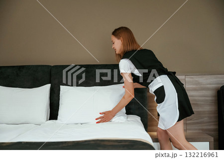 Fresh new cloth for the bed. Young chambermaid is in hotel room Fresh new cloth for the bed. Young chambermaid is in hotel room 132216961