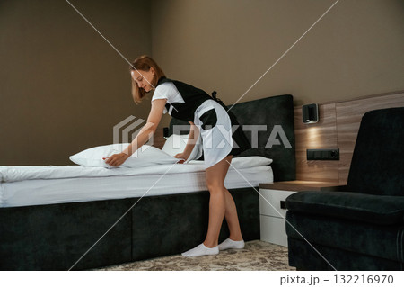 Modern interior, working. Young chambermaid is in hotel room 132216970