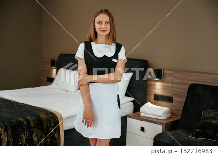 Posing, standing and smiling. Young chambermaid is in hotel room 132216983
