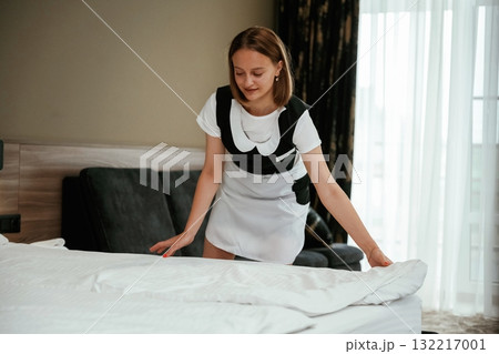 New pillowcase for the bed. Young chambermaid is in hotel room New pillowcase for the bed. Young chambermaid is in hotel room 132217001