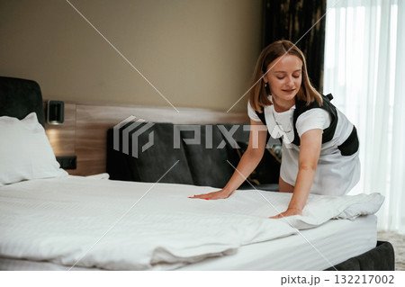 New pillowcase for the bed. Young chambermaid is in hotel room New pillowcase for the bed. Young chambermaid is in hotel room 132217002