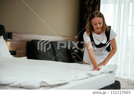 New pillowcase for the bed. Young chambermaid is in hotel room New pillowcase for the bed. Young chambermaid is in hotel room 132217003