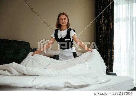 New pillowcase for the bed. Young chambermaid is in hotel room 132217004