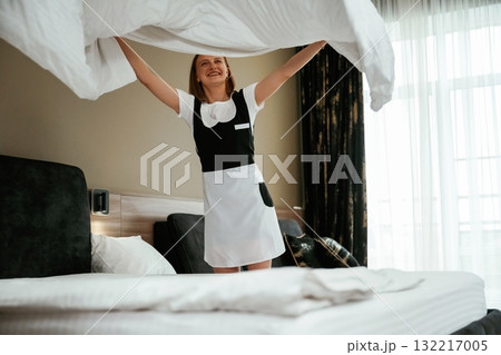 New pillowcase for the bed. Young chambermaid is in hotel room 132217005