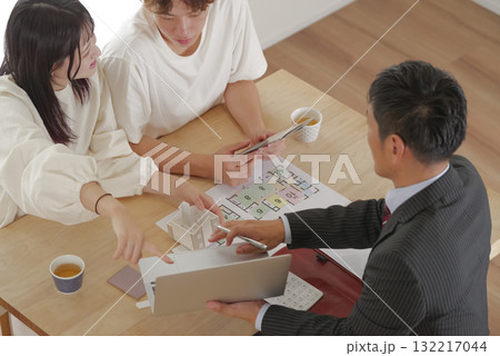営業マンと家づくりの相談をする若い夫婦 営業マンと家づくりの相談をする若い夫婦 132217044