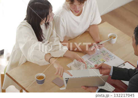 営業マンと家づくりの相談をする若い夫婦 132217045