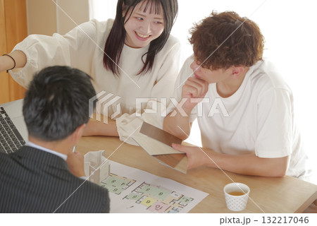 営業マンと家づくりの相談をする若い夫婦 132217046