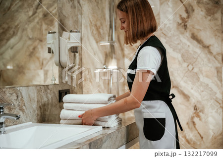 Bathroom interior. Young chambermaid is in hotel room Bathroom interior. Young chambermaid is in hotel room 132217099