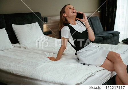 Having conversation by using phone. Young chambermaid is in hotel room Having conversation by using phone. Young chambermaid is in hotel room 132217117