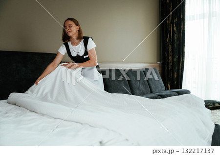 White pillowcase for the bed. Young chambermaid is in hotel room 132217137