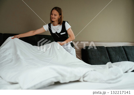 Large new pillow case on the bed. Young chambermaid is in hotel room Large new pillow case on the bed. Young chambermaid is in hotel room 132217141