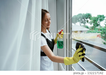 Window washing, cleaning. Young chambermaid is in hotel room Window washing, cleaning. Young chambermaid is in hotel room 132217142