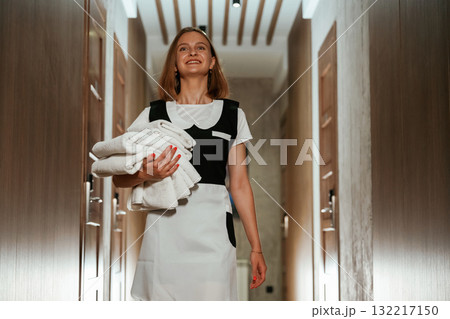 Holding fresh cloth for bed. Chambermaid is standing in the hotel corridor Holding fresh cloth for bed. Chambermaid is standing in the hotel corridor 132217150