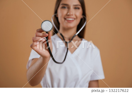 Stethoscope in hand. Young pretty woman is against background in the studio 132217622