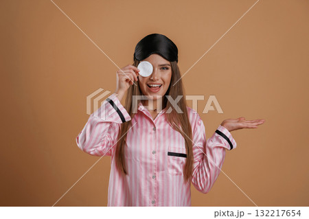 Skin care morning routine, in pink pajama. Young pretty woman is against background in the studio Skin care morning routine, in pink pajama. Young pretty woman is against background in the studio 132217654