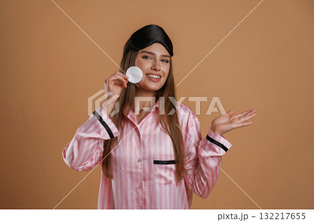 Skin care morning routine, in pink pajama. Young pretty woman is against background in the studio Skin care morning routine, in pink pajama. Young pretty woman is against background in the studio 132217655