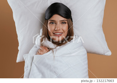 Wrapped in a blanket. Young pretty woman is against background in the studio Wrapped in a blanket. Young pretty woman is against background in the studio 132217663