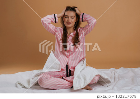 Doing morning stretches, on the ground. Young pretty woman is against background in the studio Doing morning stretches, on the ground. Young pretty woman is against background in the studio 132217679