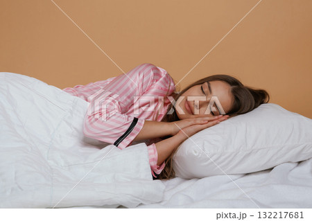 Sleeping in the bed. Young pretty woman is against background in the studio Sleeping in the bed. Young pretty woman is against background in the studio 132217681