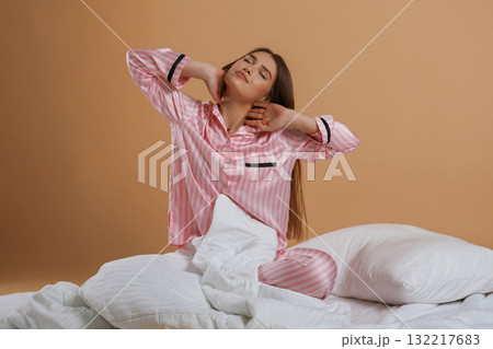 Doing morning stretches, on the ground. Young pretty woman is against background in the studio 132217683