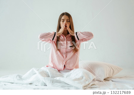 Rest conception, waking up, on the white blanket. Young pretty woman is against background in the studio 132217689