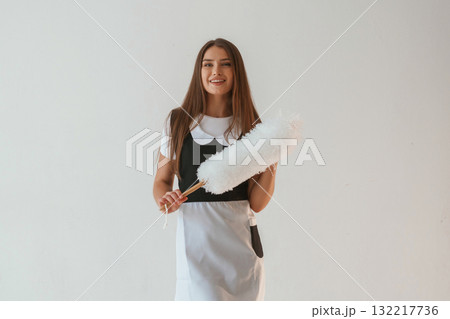 Positive, chambermaid is holding cleaning thing. Young pretty woman is against background in the studio Positive, chambermaid is holding cleaning thing. Young pretty woman is against background in the studio 132217736