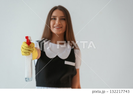 Chambermaid is with cleaning product and tool. Young pretty woman is against background in the studio 132217743
