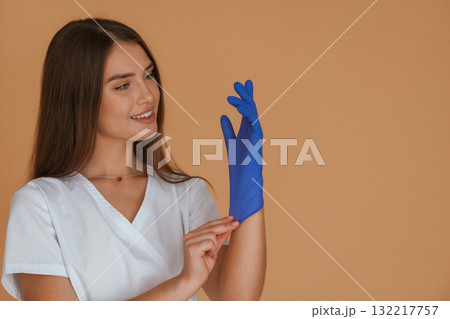 Blue glove, smiling nurse. Young pretty woman is against background in the studio Blue glove, smiling nurse. Young pretty woman is against background in the studio 132217757