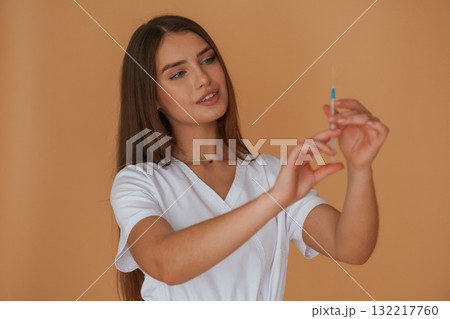Vaccination concept, nurse is with syringe. Young pretty woman is against background in the studio 132217760