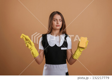 Unsatisfied chambermaid. Young pretty woman is against background in the studio Unsatisfied chambermaid. Young pretty woman is against background in the studio 132217779