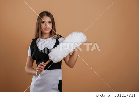 Occupation of chambermaid. Young pretty woman is against background in the studio Occupation of chambermaid. Young pretty woman is against background in the studio 132217811