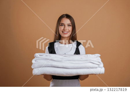Brand new towels, chambermaid is standing. Young pretty woman is against background in the studio Brand new towels, chambermaid is standing. Young pretty woman is against background in the studio 132217819