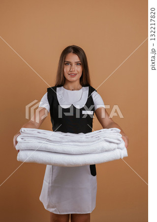 Brand new towels, chambermaid is standing. Young pretty woman is against background in the studio Brand new towels, chambermaid is standing. Young pretty woman is against background in the studio 132217820