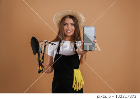 Modern technology, smartphone with copy space, gardener. Young pretty woman is against background in the studio 132217872