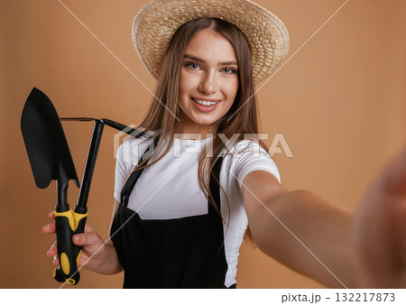 Labor conception. Gardener is with tools. Young pretty woman is against background in the studio 132217873