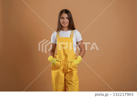 Hands in pockets, gardener is standing. Young pretty woman is against background in the studio 132217903