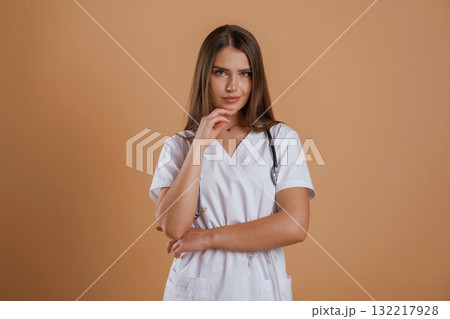 Pretty nurse is in white clothes. Young woman is against background in the studio 132217928