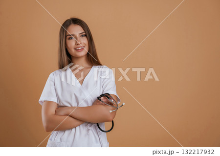 Pretty nurse is in white clothes. Young woman is against background in the studio 132217932