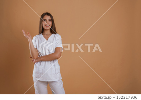 Cheerful nurse. Young pretty woman is against background in the studio Cheerful nurse. Young pretty woman is against background in the studio 132217936