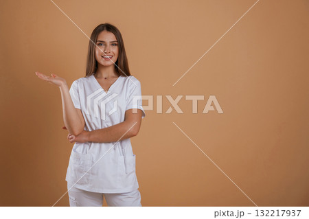 Cheerful nurse. Young pretty woman is against background in the studio Cheerful nurse. Young pretty woman is against background in the studio 132217937