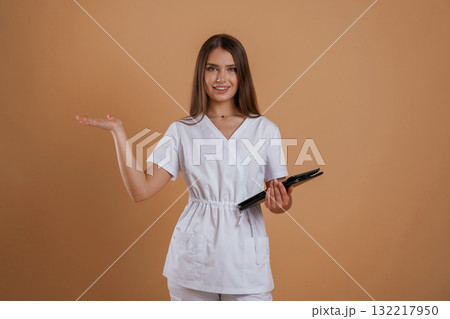 Digital tablet in hands of doctor. Young pretty woman is against background in the studio 132217950