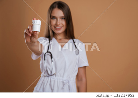Pills in hands of doctor or a nurse. Young pretty woman is against background in the studio Pills in hands of doctor or a nurse. Young pretty woman is against background in the studio 132217952