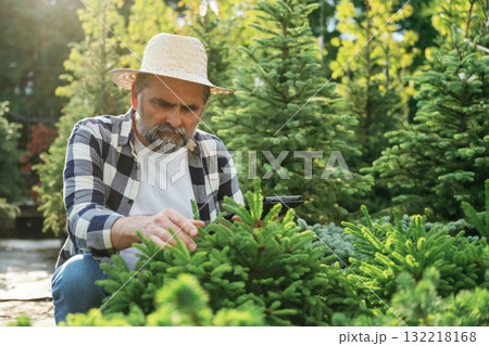 Black digital tablet in hand. Senior gardener is at work at daytime Black digital tablet in hand. Senior gardener is at work at daytime 132218168